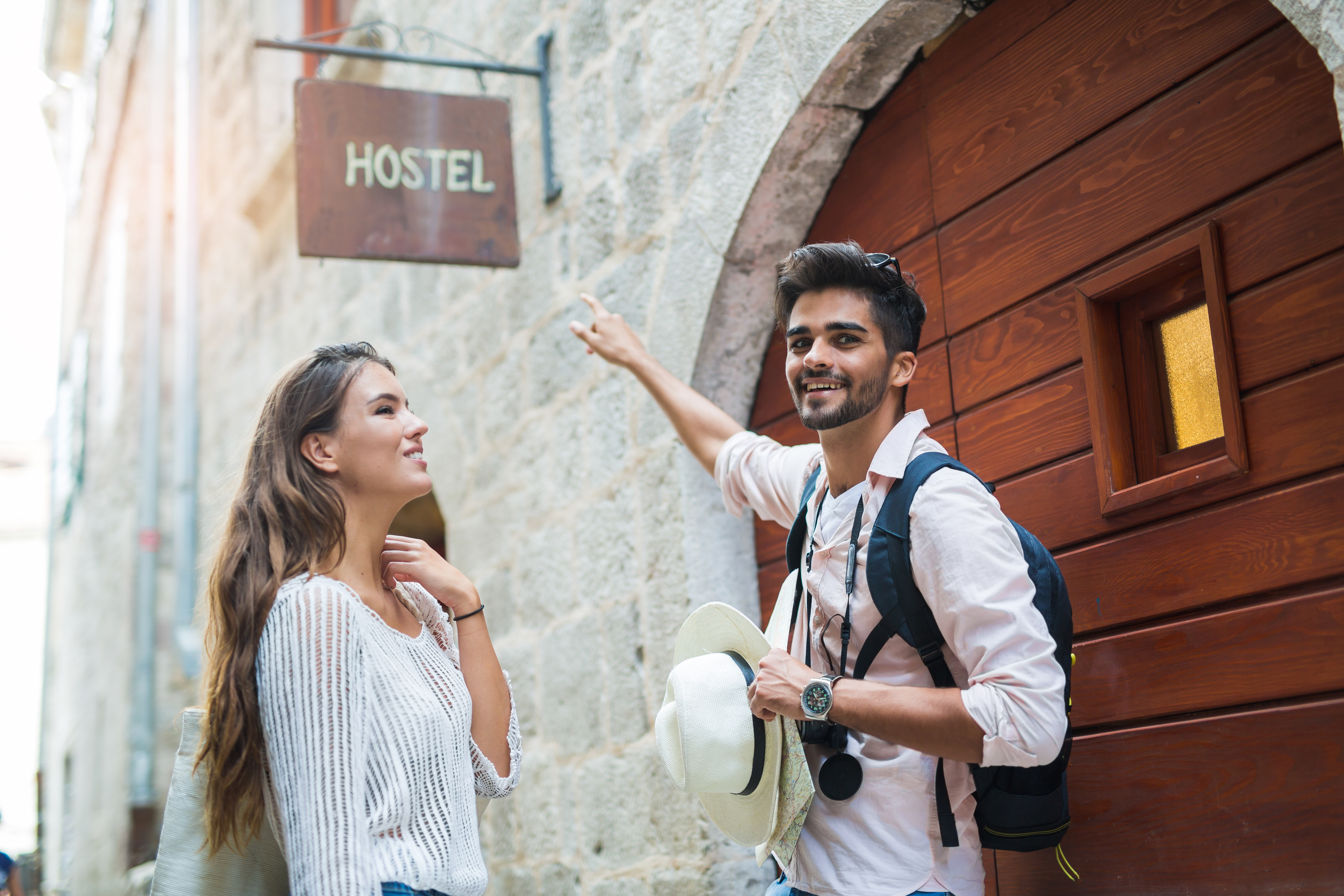 Tourist couple enjoying sightseeing and exploring city pointing a finger at hostel